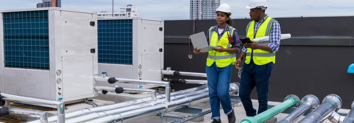 Industrial engineers on roof next to ventilation systems (cropped)