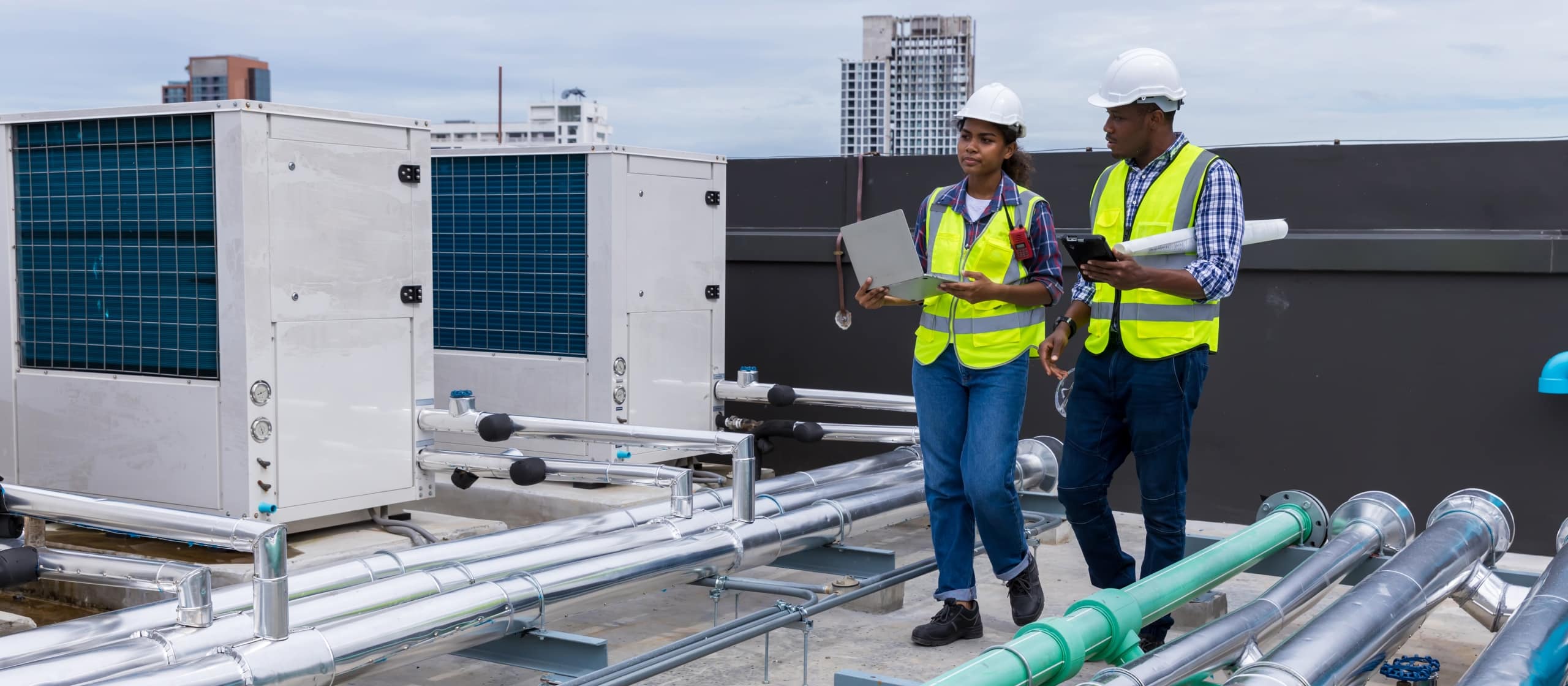 Industrial engineers on roof next to ventilation systems (cropped)
