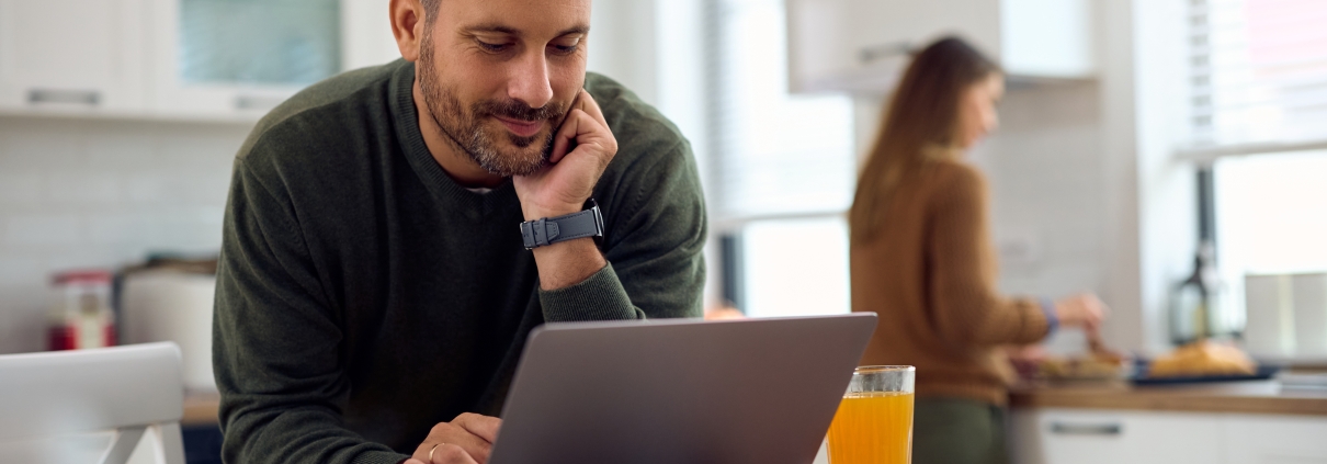 Smiling man on a laptop in the kitchen