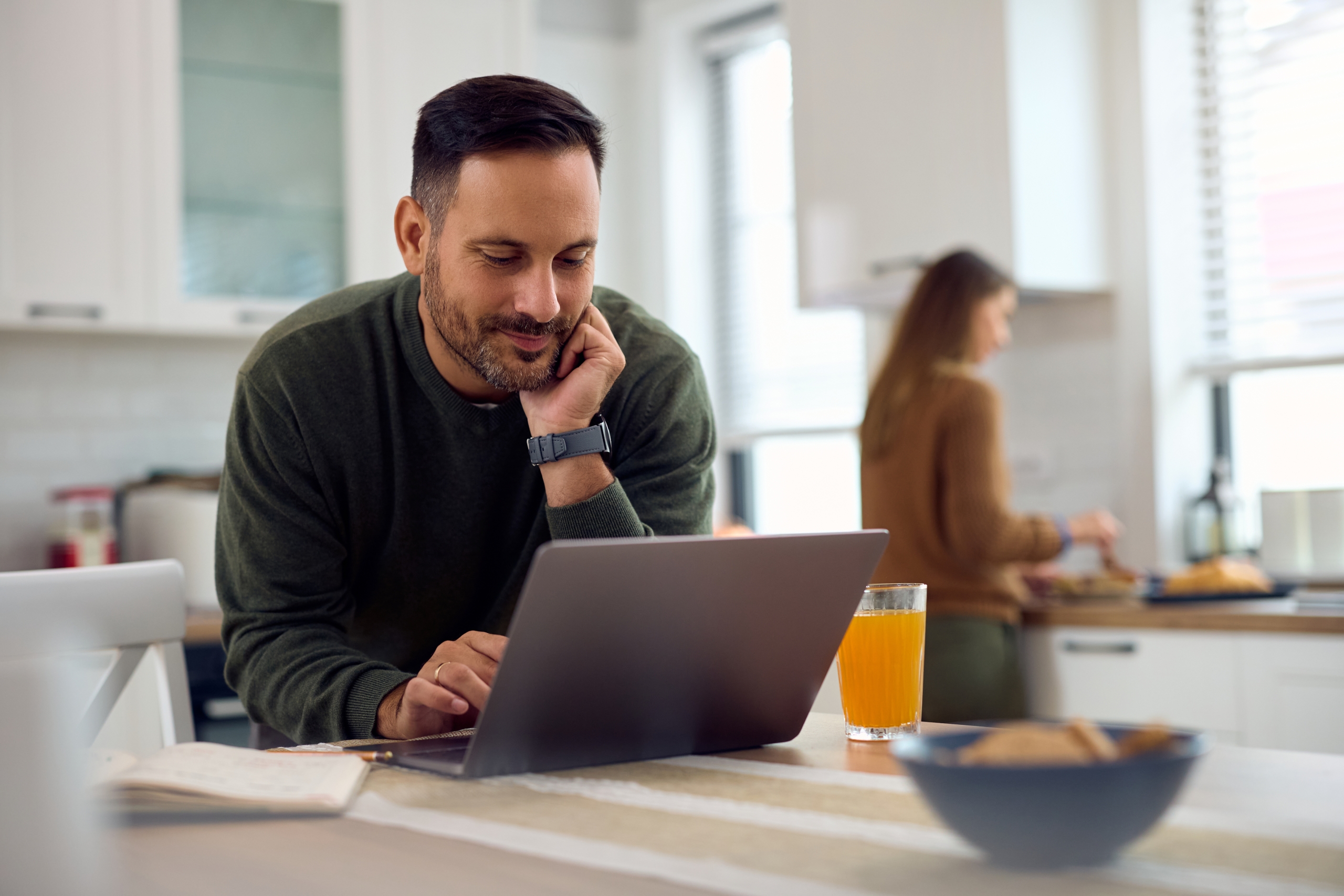 Smiling man on a laptop in the kitchen