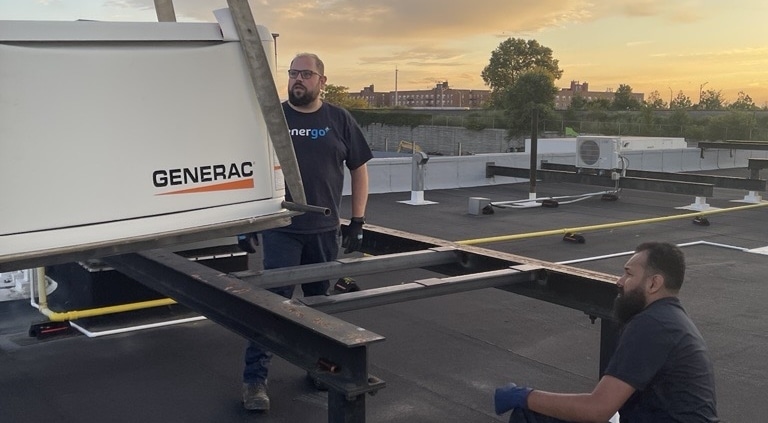 Energo technicians installing Generac generator on rooftop at sunset