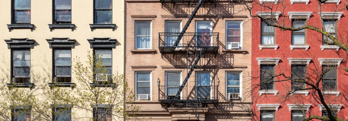 Row of NYC brownstone apartment buildings in sunlight