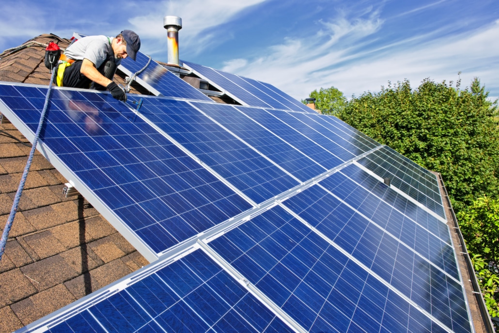 Man installing solar panels on roof of house