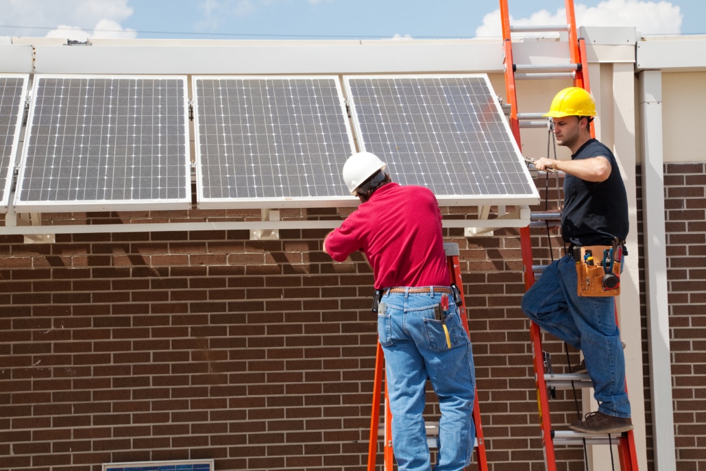 Installers placing solar panels on a brick home roof