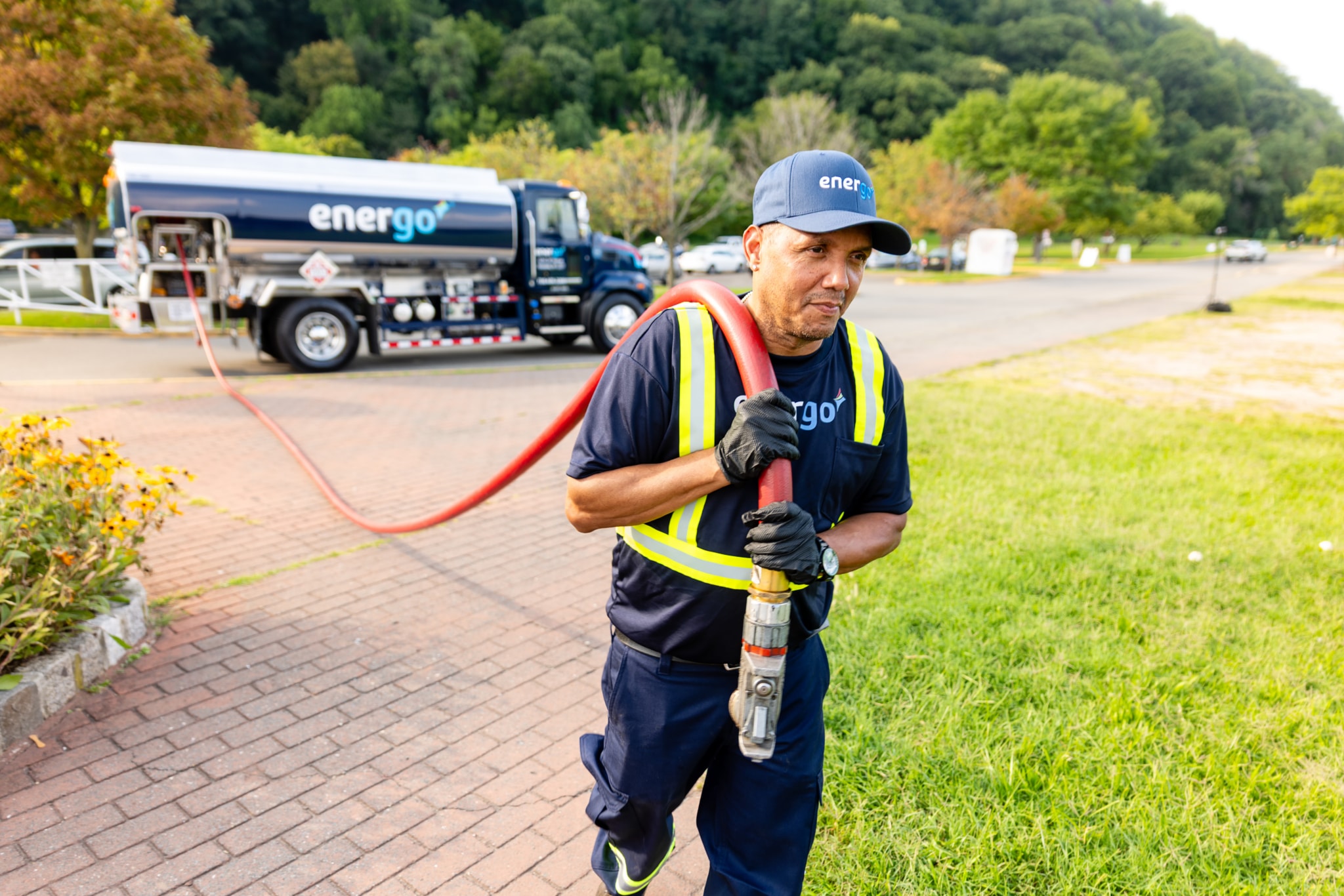 Energo delivery employee carrying a heating oil hose with a branded tanker truck behind him