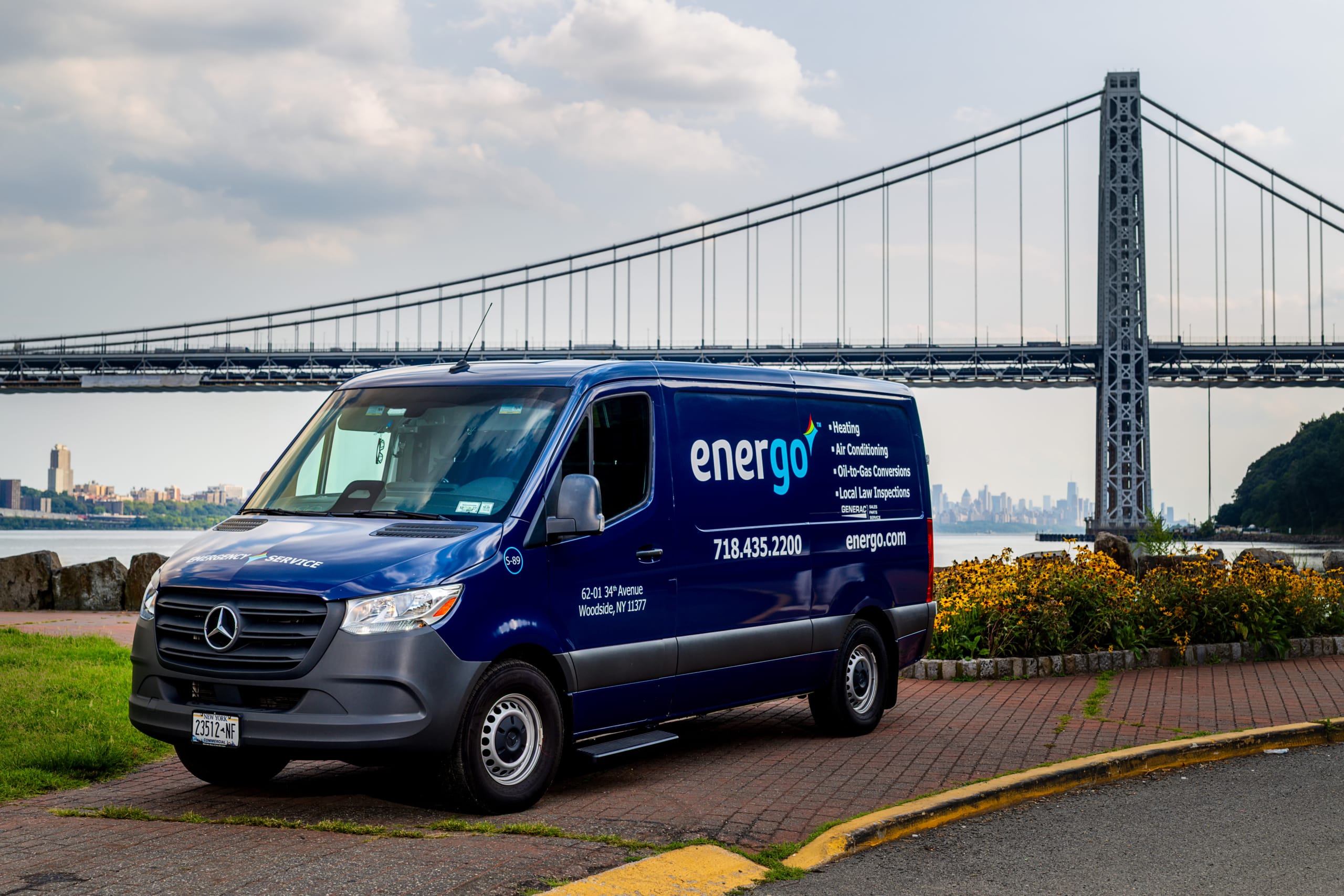 Blue Energo service van parked beside the river with a suspension bridge in the background